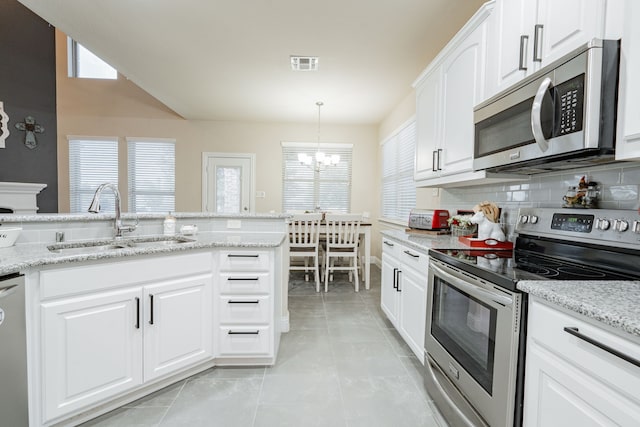 kitchen with sink, backsplash, white cabinetry, appliances with stainless steel finishes, and an inviting chandelier