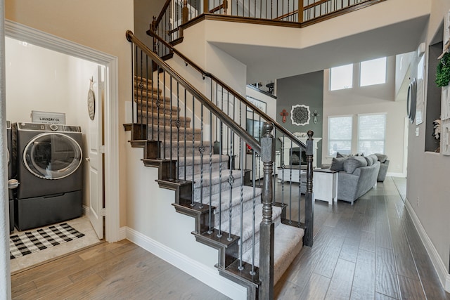 stairs featuring wood-type flooring, a high ceiling, and washer / clothes dryer