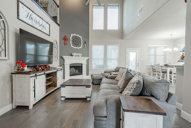 living room with a towering ceiling, a chandelier, and dark wood-type flooring