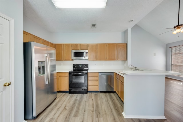 kitchen featuring light hardwood / wood-style floors, kitchen peninsula, stainless steel appliances, lofted ceiling, and sink