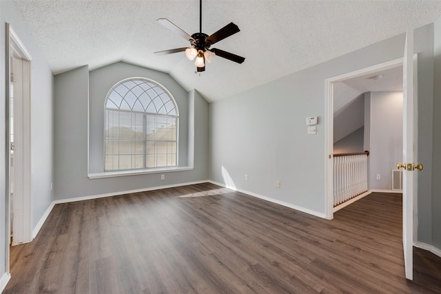 spare room featuring a textured ceiling, lofted ceiling, dark wood-type flooring, and ceiling fan