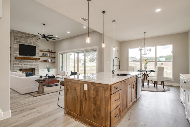 kitchen featuring ceiling fan with notable chandelier, a wealth of natural light, light wood-type flooring, and a fireplace