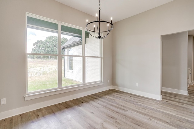 unfurnished dining area with light hardwood / wood-style flooring, plenty of natural light, and a chandelier