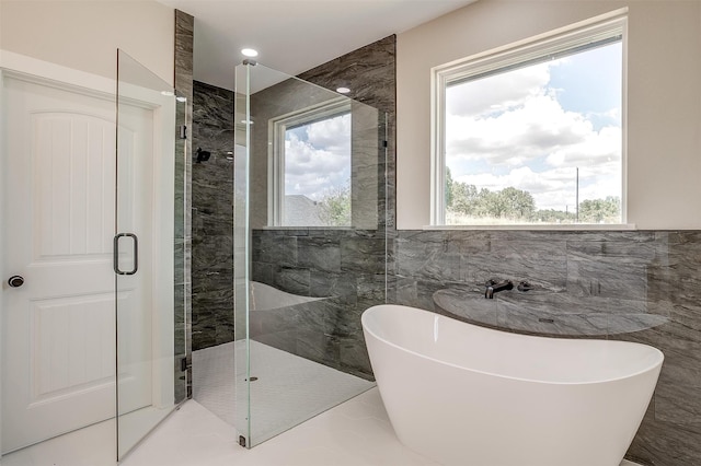 bathroom with tile walls and independent shower and bath