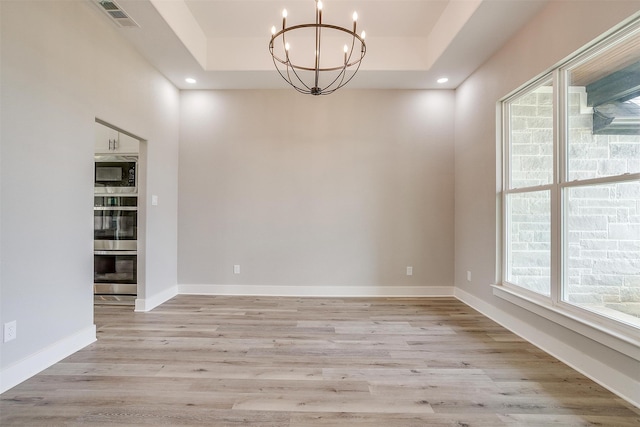 unfurnished dining area with a raised ceiling, light hardwood / wood-style flooring, and plenty of natural light