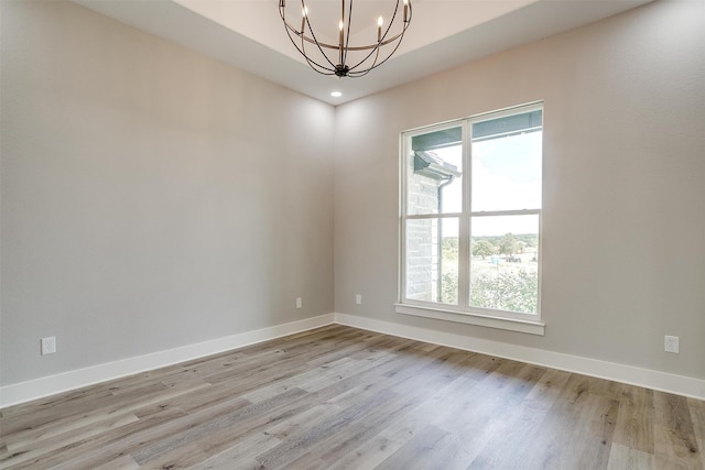 spare room featuring a notable chandelier and light wood-type flooring