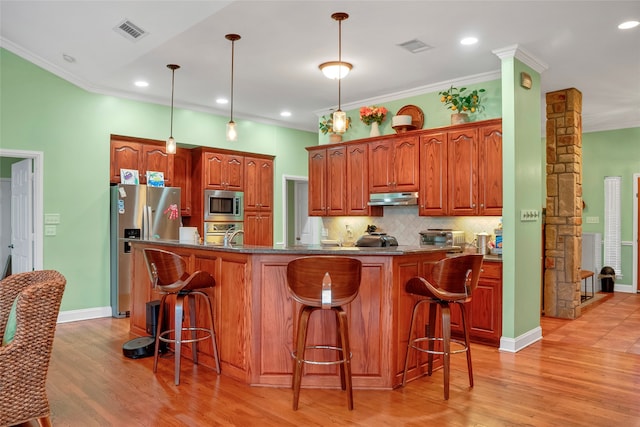 kitchen featuring a center island with sink, stainless steel appliances, light wood-type flooring, and a kitchen breakfast bar