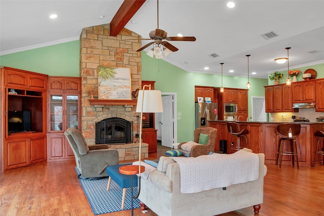 living room featuring a fireplace, light wood-type flooring, crown molding, ceiling fan, and vaulted ceiling with beams