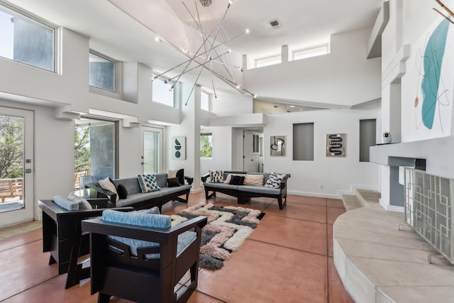 tiled living area featuring a notable chandelier, baseboards, and a towering ceiling