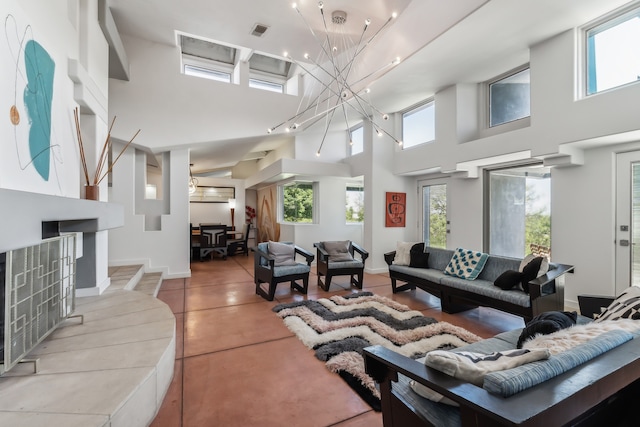 living area featuring a wealth of natural light, visible vents, an inviting chandelier, and a towering ceiling