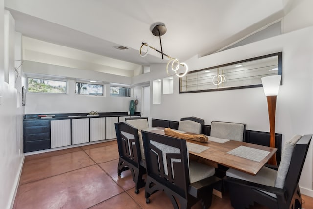 dining area with tile patterned floors, visible vents, baseboards, and vaulted ceiling