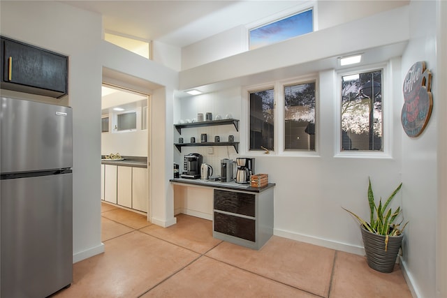 kitchen featuring open shelves, baseboards, and freestanding refrigerator