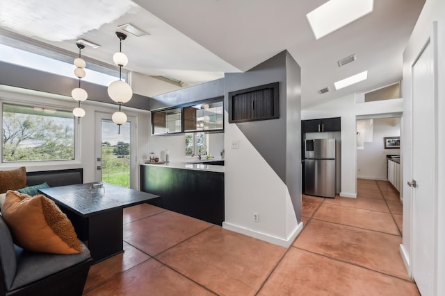 kitchen featuring visible vents, hanging light fixtures, vaulted ceiling, and freestanding refrigerator