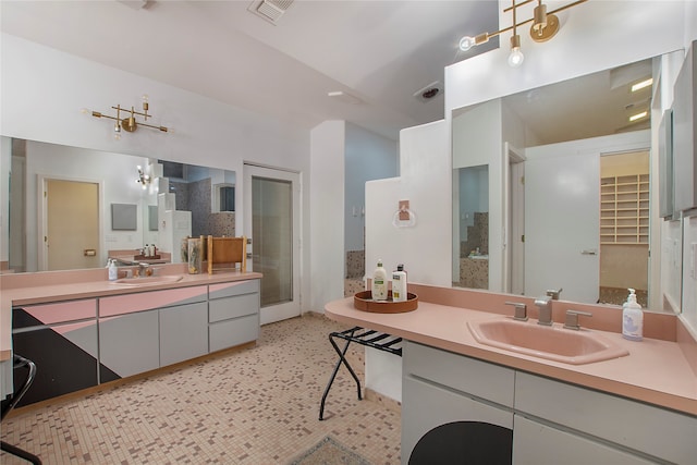 bathroom featuring visible vents, a shower stall, two vanities, and a sink