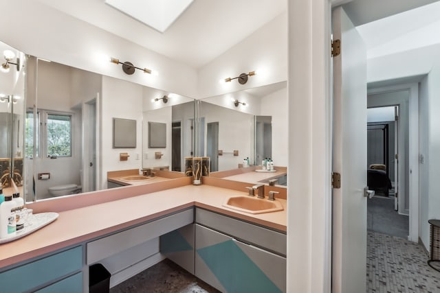 bathroom featuring a sink, lofted ceiling, toilet, and double vanity