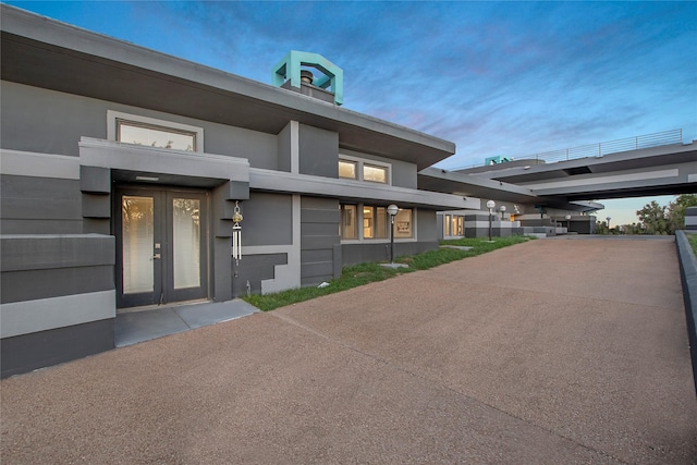 exterior entry at dusk with french doors and stucco siding