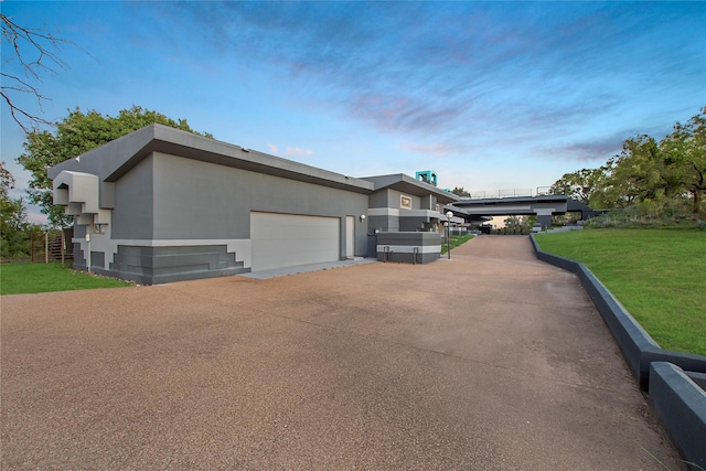 view of property exterior featuring a lawn, a garage, driveway, and stucco siding