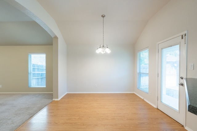 unfurnished dining area featuring light hardwood / wood-style flooring, vaulted ceiling, and an inviting chandelier