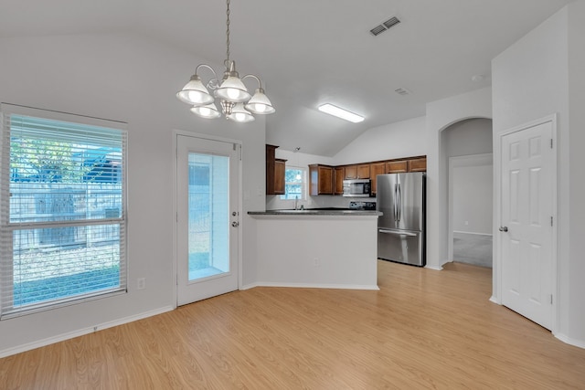 kitchen featuring light wood-type flooring, vaulted ceiling, kitchen peninsula, hanging light fixtures, and stainless steel appliances