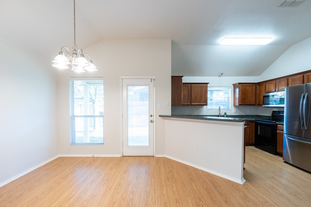 kitchen featuring a notable chandelier, stainless steel appliances, vaulted ceiling, and light hardwood / wood-style floors