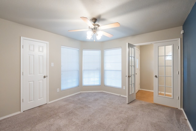 unfurnished room with ceiling fan, light carpet, and french doors