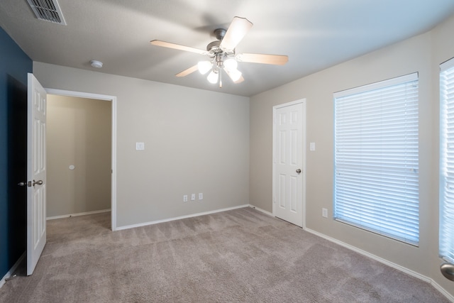 unfurnished room featuring ceiling fan, light colored carpet, and a wealth of natural light