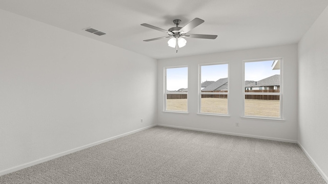 spare room with ceiling fan, carpet floors, visible vents, and baseboards