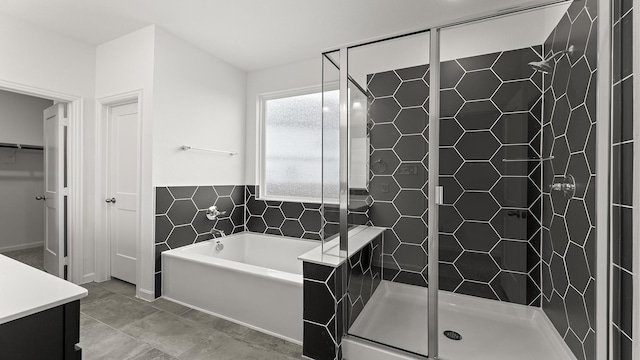 bathroom with a stall shower, tile patterned flooring, a spacious closet, vanity, and a bath