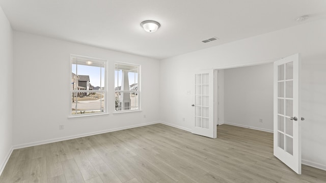 empty room with baseboards, french doors, visible vents, and light wood-style floors