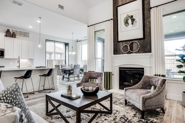 living room featuring light hardwood / wood-style flooring, a chandelier, and sink