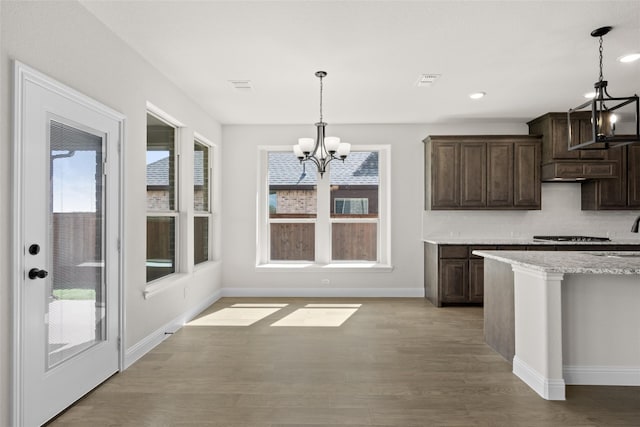 kitchen with light wood-type flooring, an inviting chandelier, dark brown cabinets, and plenty of natural light