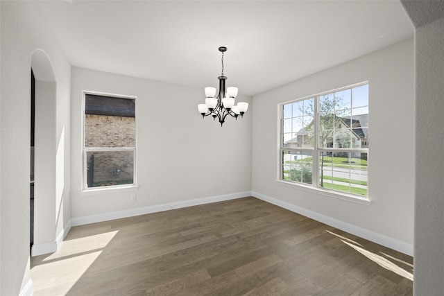 empty room with wood-type flooring and a chandelier