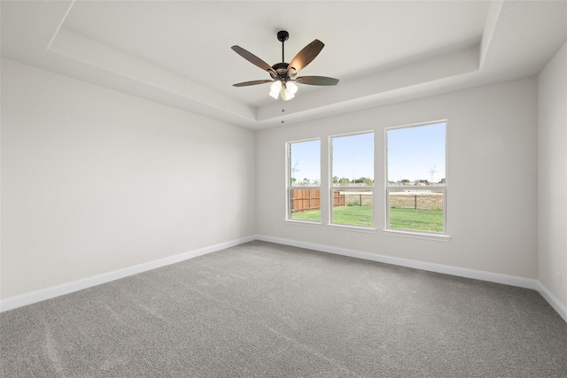 carpeted empty room featuring ceiling fan and a raised ceiling