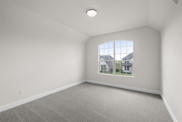 carpeted empty room featuring lofted ceiling