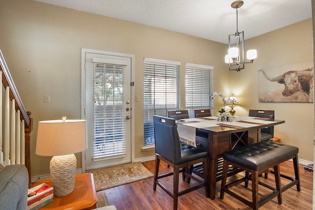 dining space with hardwood / wood-style floors and an inviting chandelier