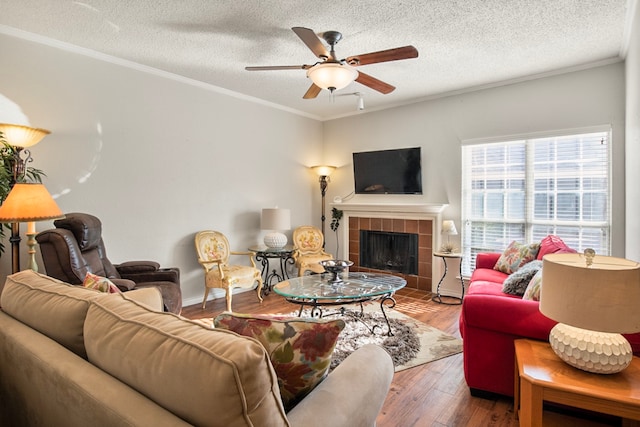 living room featuring ceiling fan, ornamental molding, a fireplace, and hardwood / wood-style floors