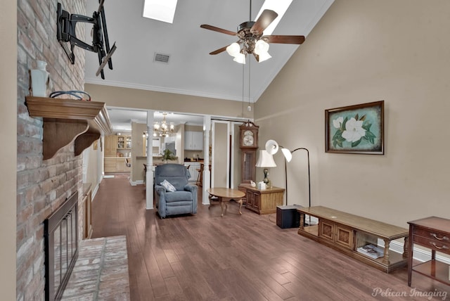 living room with high vaulted ceiling, a brick fireplace, ceiling fan with notable chandelier, crown molding, and wood-type flooring