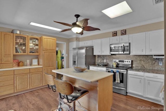 kitchen with ornamental molding, light wood-type flooring, ceiling fan, and appliances with stainless steel finishes