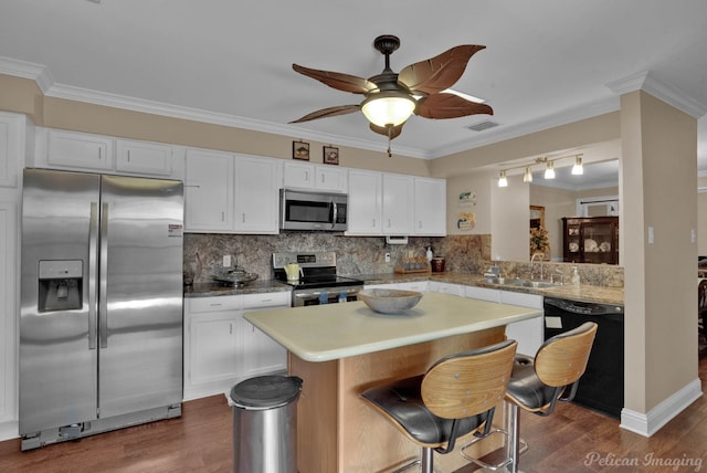 kitchen with dark wood-type flooring, white cabinets, stainless steel appliances, crown molding, and ceiling fan