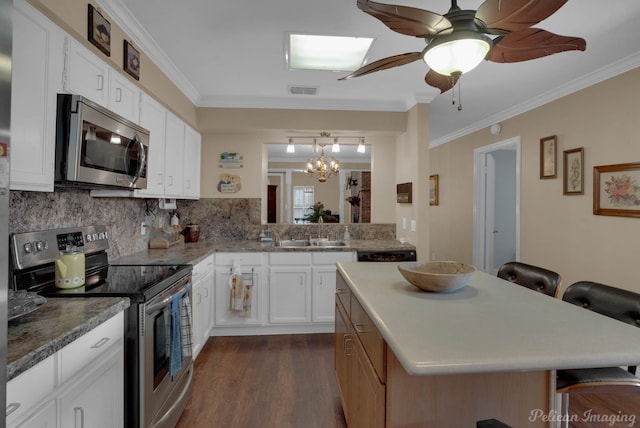 kitchen with white cabinets, sink, stainless steel appliances, a kitchen breakfast bar, and ceiling fan with notable chandelier