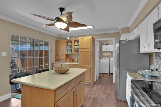 kitchen featuring ceiling fan, a kitchen island, washer and dryer, crown molding, and hardwood / wood-style floors