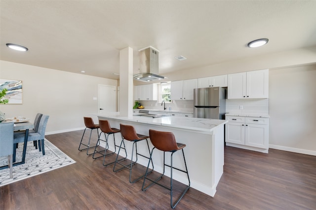 kitchen featuring dark hardwood / wood-style floors, range hood, white cabinetry, decorative backsplash, and stainless steel fridge