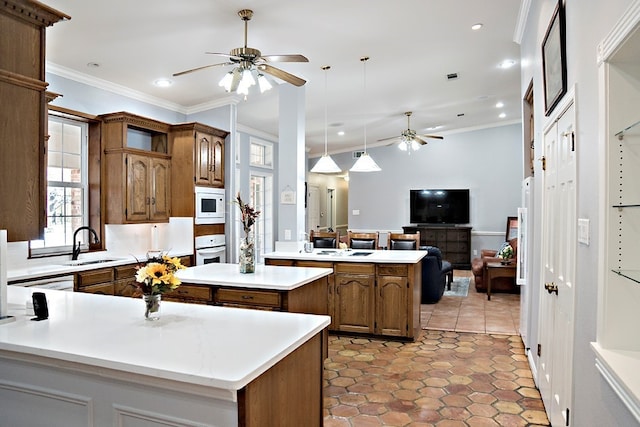 kitchen with a center island, sink, white appliances, crown molding, and ceiling fan