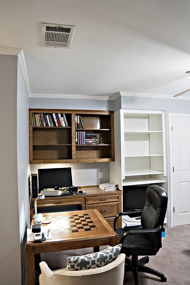 office with a textured ceiling, built in desk, crown molding, and carpet flooring