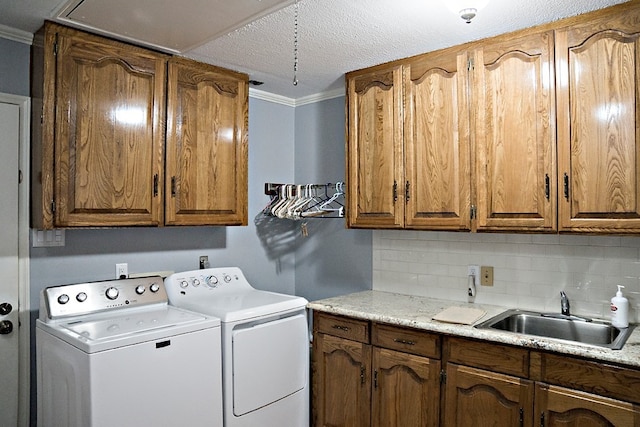 laundry area with washer and clothes dryer, crown molding, sink, and cabinets