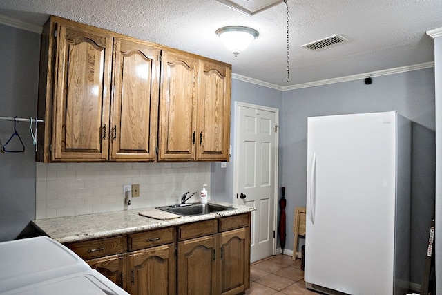 kitchen featuring light tile patterned floors, sink, backsplash, crown molding, and white fridge