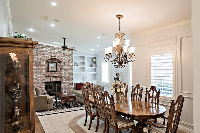 dining space with ceiling fan with notable chandelier, a fireplace, ornamental molding, and lofted ceiling