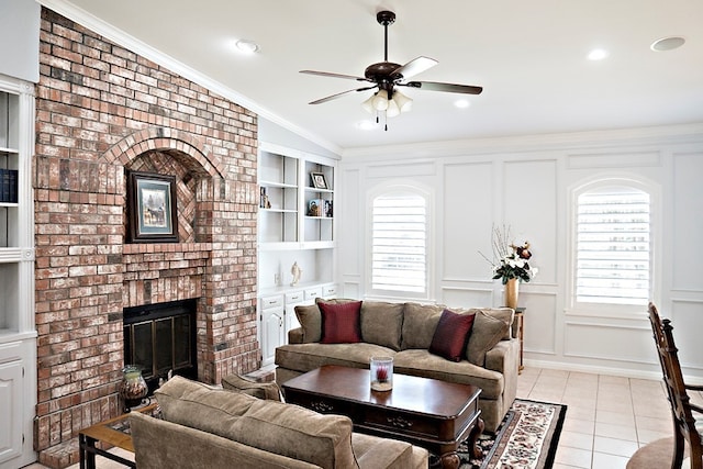 living room featuring built in shelves, a fireplace, light tile patterned floors, ornamental molding, and ceiling fan