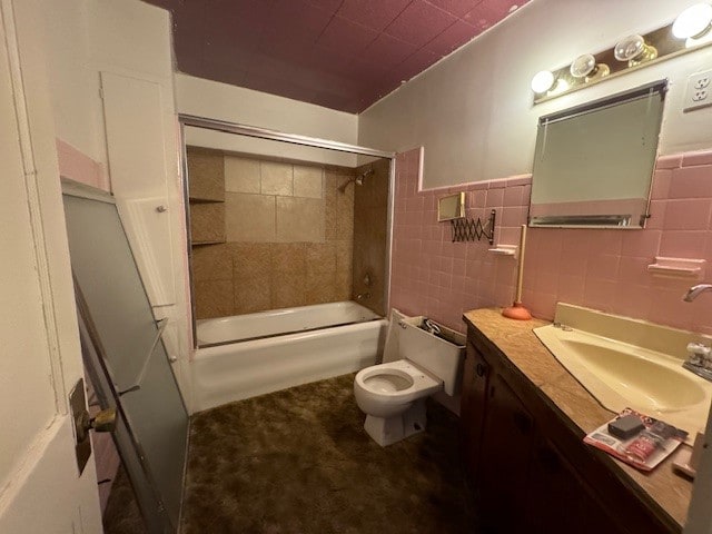 full bathroom with tiled shower / bath, vanity, tile walls, and toilet