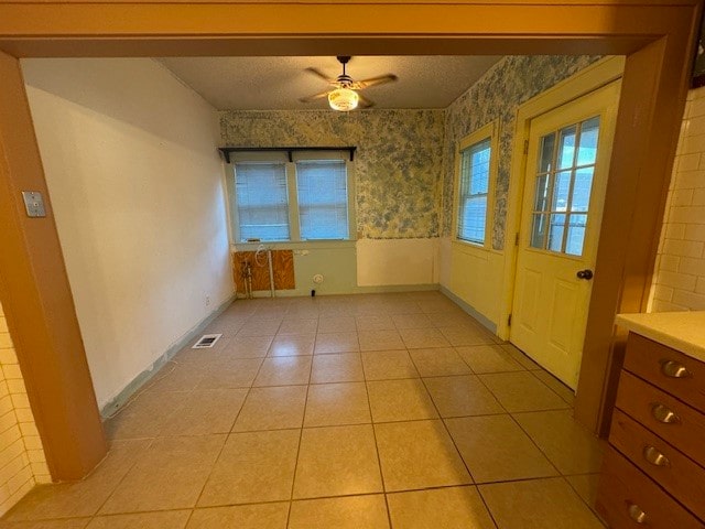 tiled empty room featuring ceiling fan and a textured ceiling